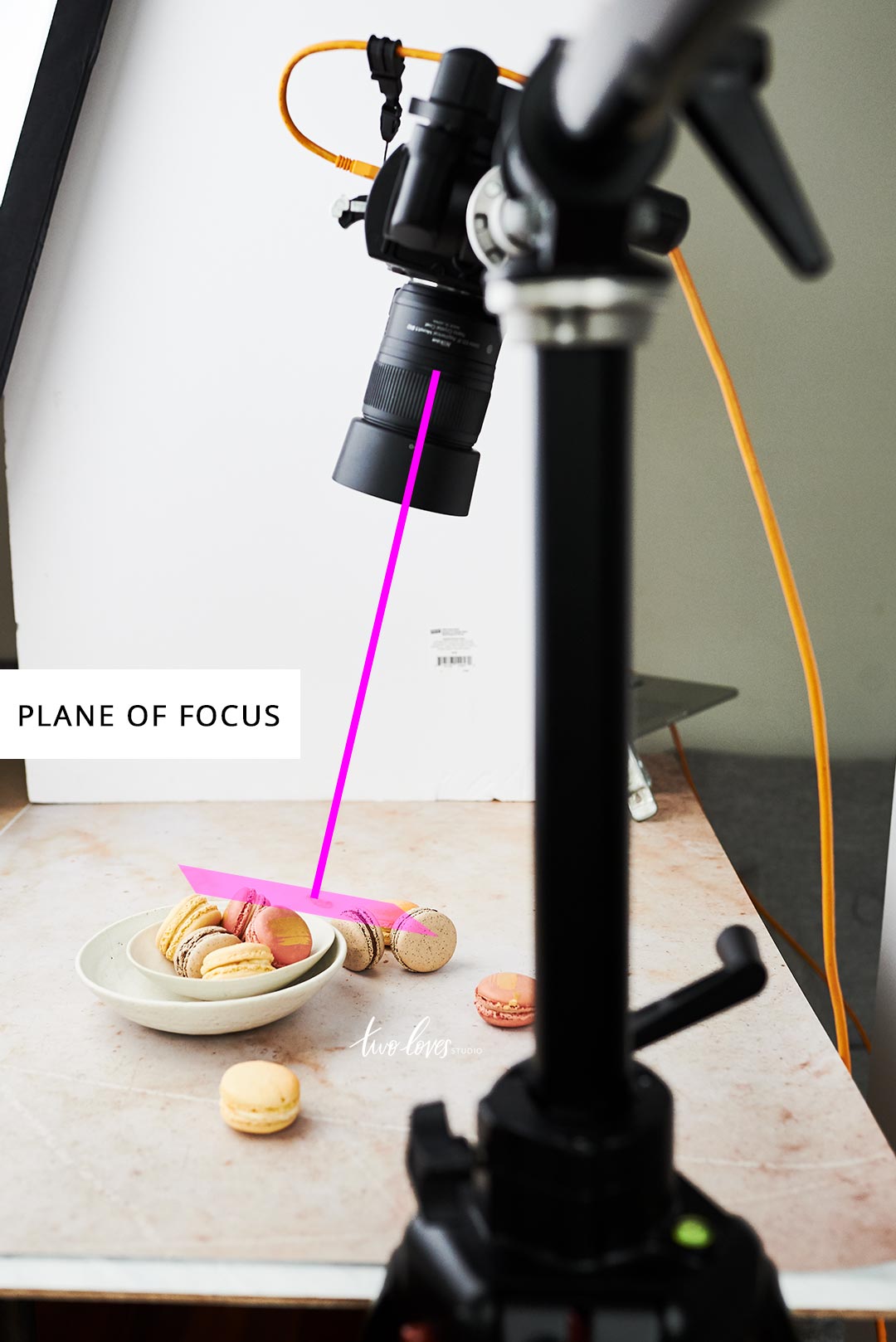 Macaroons in a white bowl and a camera set up for a photo